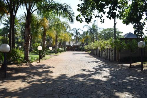 a cobblestone road with palm trees and a fence at Thabong Bed and Breakfast in Brakpan