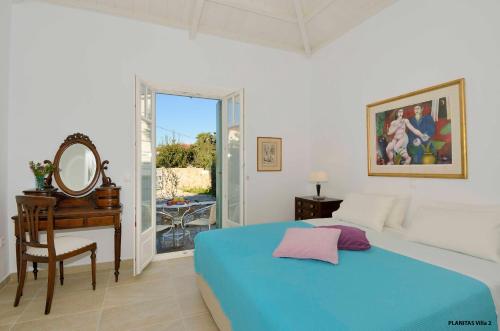 a bedroom with a bed and a desk and a mirror at Planitas Villas in Skopelos Town
