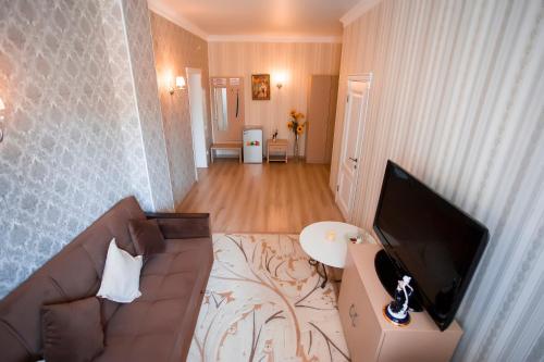 a living room with a couch and a flat screen tv at Aruna Hotel in Astana