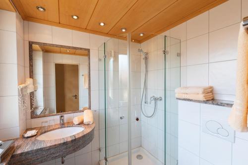 a bathroom with a glass shower and a sink at Landgasthof Paradies in Frickingen
