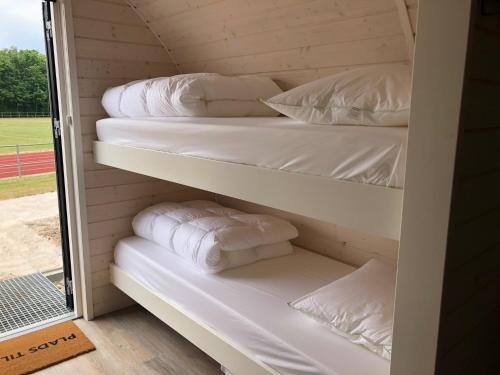 Zimmer mit weißen Kissen und Handtüchern auf Regalen in der Unterkunft Danhostel Maribo in Maribo