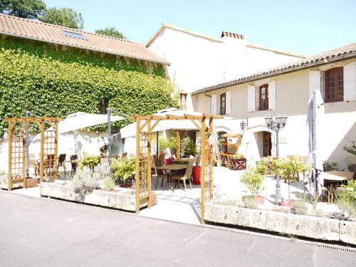 a patio with a table and chairs and a building at Le Chapeau Rouge in Lusignan