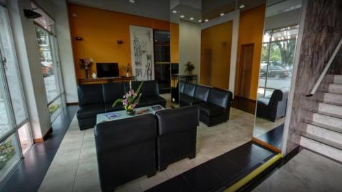 a living room with black leather chairs and a table at Rede Andrade Guaíra in Curitiba