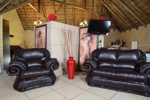 two leather chairs and a television in a room at Thabong Bed and Breakfast in Brakpan