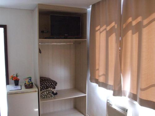 a room with a tv and a shelf with a television at Rede Andrade Guaíra in Curitiba