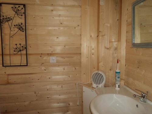 La salle de bains est pourvue de murs en bois et d'un lavabo. dans l'établissement La Bastide de la Reine Margot, à Beaumont