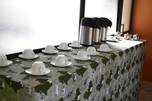 a table with white cups and saucers on it at Africa Lodge Arusha in Nkoaranga