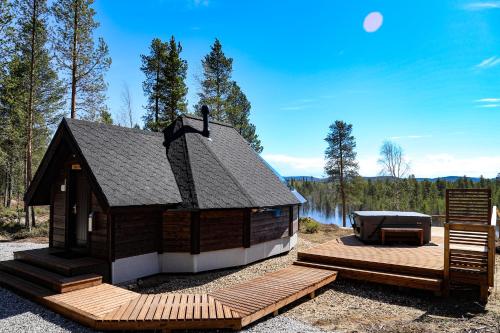 a small cabin with a deck and a hot tub at Aurora Village Ivalo in Ivalo