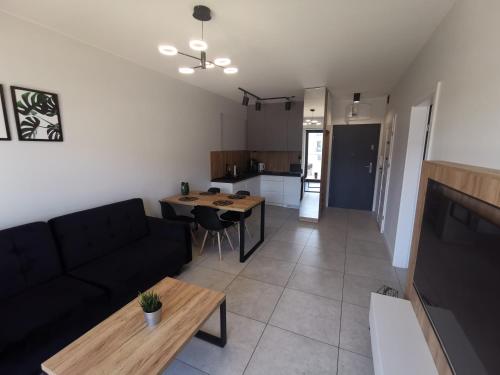 a living room and kitchen with a couch and a table at Apartament Gardenia Klif 35 z widokiem na morze in Dziwnów