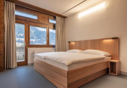 um quarto com uma cama e uma grande janela em Sport Resort Fiesch, Garni Goneri em Fiesch