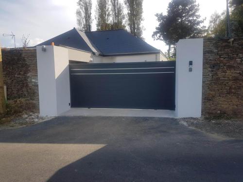 a blue and white garage door with a brick wall at Studio Castel Binic in Pordic