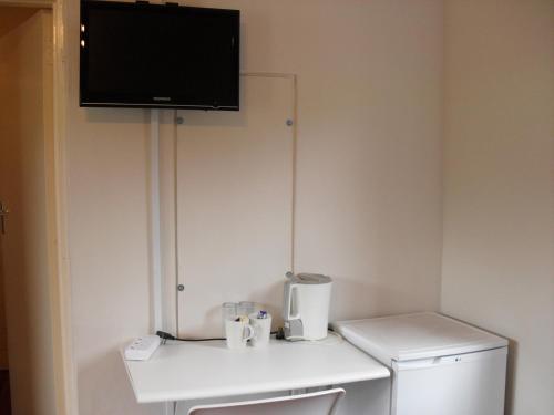 a small bathroom with a refrigerator and a tv on the wall at Juffroushoogte Gaste Plaas in Vredenburg