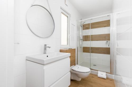 a white bathroom with a toilet and a mirror at Yellow House Dziwnów in Dziwnów