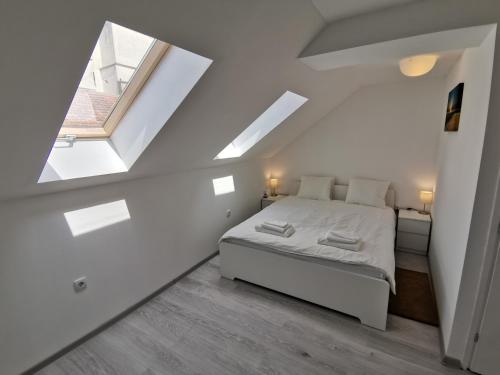 a white bedroom with a bed and a window at RIS CENTRAL Apartments in Novi Sad