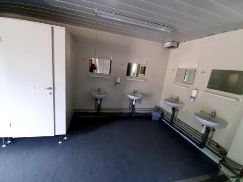 a bathroom with three sinks and a person in the mirror at Camping und Chalet Saggraben in Palfau