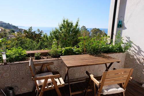 a wooden table and two chairs on a balcony at Rosalia's apartments in Castel di Tusa
