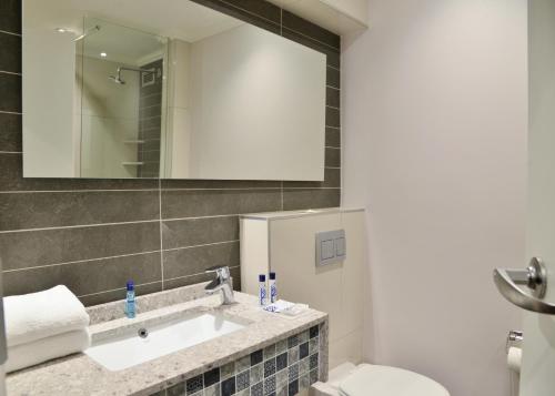 uma casa de banho com um lavatório, um WC e um espelho. em Town Lodge Menlo Park em Pretoria