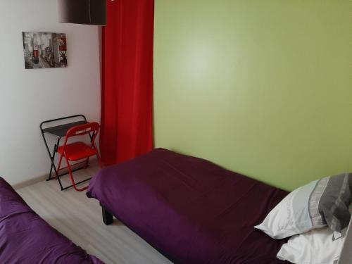 een slaapkamer met een bed en een rood gordijn en een stoel bij LE GERLE in Mercurol
