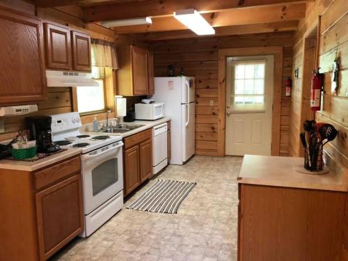 a large kitchen with white appliances and wooden cabinets at Country Road Cabins in Hico