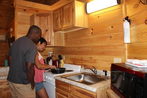 a man and a woman standing in a kitchen at Country Road Cabins in Hico