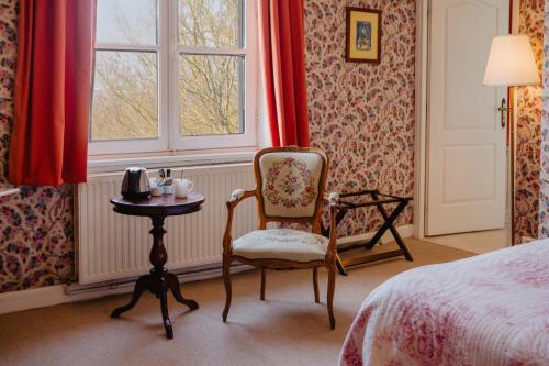 a bedroom with a bed and a chair and a table at Domaine Le Parc in Danizy