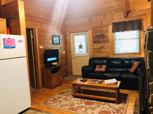 a living room with a black leather couch and a table at Country Road Cabins in Hico