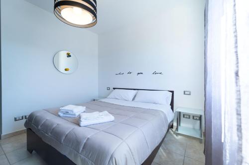 a white bedroom with a bed with two towels on it at Sweet Sea in Alghero