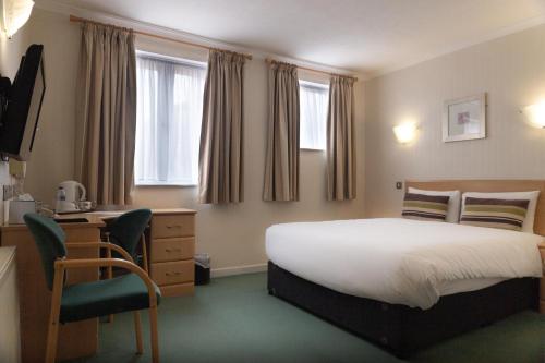 a bedroom with a bed and a desk and a chair at Wycliffe Hotel in Stockport
