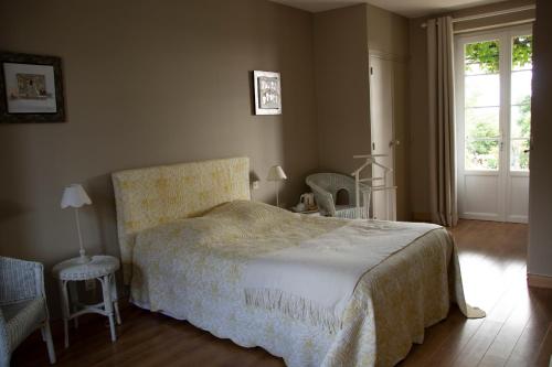 a bedroom with a bed and two chairs and a window at Chambres d'Hôtes La Pocterie in Vouneuil-sur-Vienne