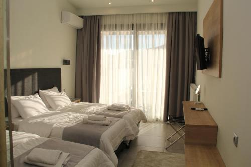 Una habitación de hotel con dos camas y una ventana. en Alexiou Hotel, en Kalambaka