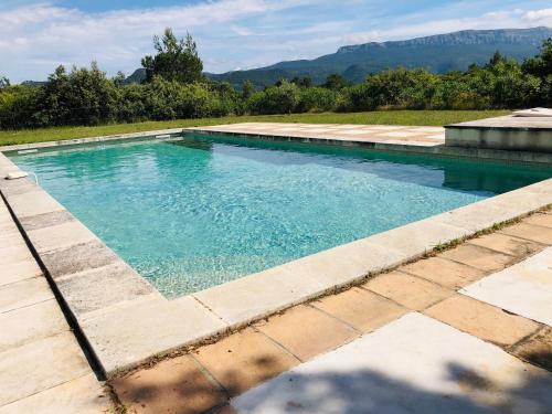 een zwembad met blauw water en bergen op de achtergrond bij La Bergerie in Saint-Maximin-la-Sainte-Baume