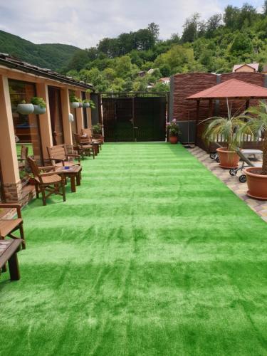 a green lawn with chairs and an umbrella at Casa Piri in Anina