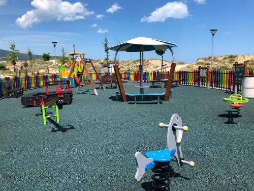a playground with colorful play equipment and an umbrella at Hotel Ancora Beach in Primorsko