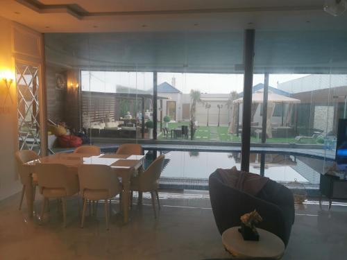 a dining room with a table and chairs and a pool at Alreem challet in Abha