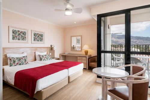 een slaapkamer met een bed, een tafel en een raam bij Buganvilia Studio Hotel in Funchal