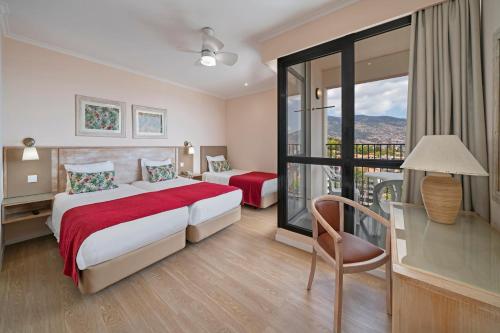 a hotel room with two beds and a balcony at Buganvilia Studio Hotel in Funchal