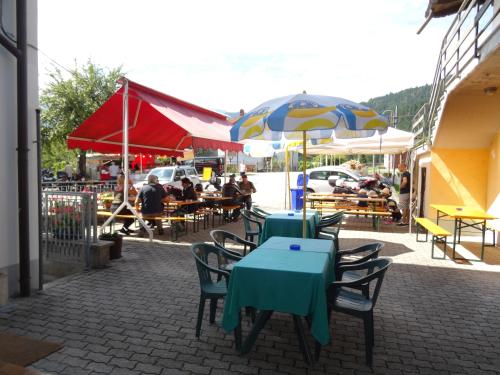 un groupe de tables et de chaises avec parasols dans une rue dans l'établissement Hotel Galles, à Paluzza