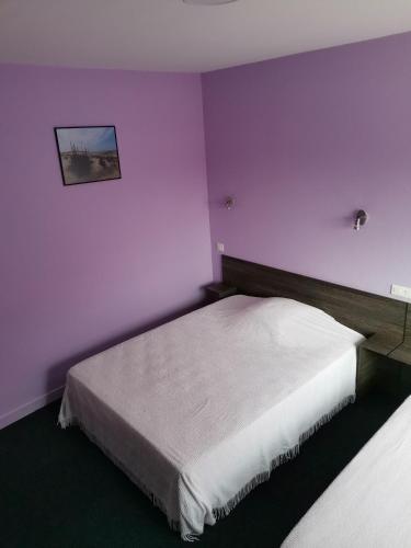 a bedroom with purple walls and a white bed at Hôtel Bar des Arènes in Pontonx-sur-lʼAdour