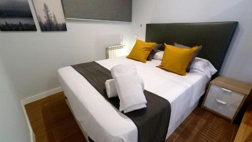 1 dormitorio con 1 cama blanca grande con almohadas amarillas en APARTAMENTOS EL POZO AMARGO, en Toledo