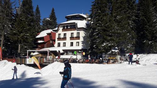 a group of people skiing in the snow in front of a building at Apartman sa terasom Vila Mina Kopaonik in Kopaonik