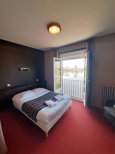 a bedroom with a large bed and a large window at Hôtel Restaurant du Lac in Combourg