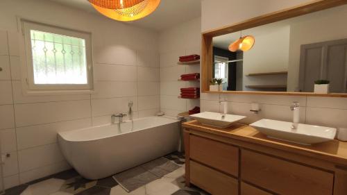 ein Badezimmer mit zwei Waschbecken, einer Badewanne und einem Spiegel in der Unterkunft La Villa Moursoise 4 Etoiles in Mours-Saint-EusÃ¨be