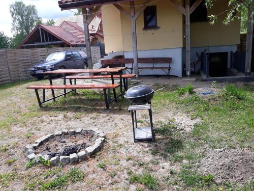 a barbecue grill and picnic tables in a yard at Dom pod Wierzbami in Gołdap
