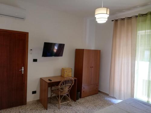 a room with a desk and a television on a wall at Appartamento City in Palmi