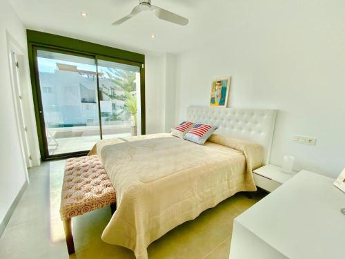 a white bedroom with a bed and a window at CHALET CON PISCINA PRIVADA EN LA URB. DE PUERTO REY in Los Amarguillos