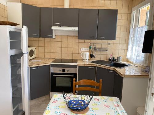 une cuisine avec des placards gris et une table avec un panier dans l'établissement RESIDENCE VALLON PARADIS, à Gréoux-les-Bains