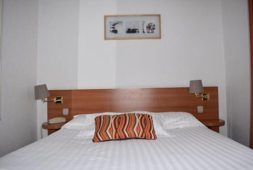 a bed with a wooden headboard with a pillow on it at Hotel Colbert in Saint-Jean-de-Luz