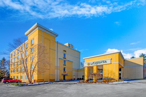 a yellow building with a car parked in a parking lot at La Quinta by Wyndham Danbury in Danbury
