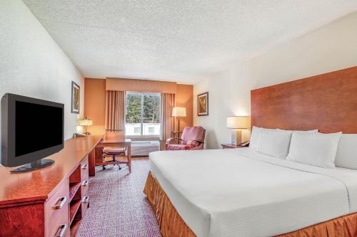 a hotel room with a bed and a flat screen tv at La Quinta by Wyndham Danbury in Danbury