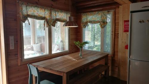 a wooden table in a kitchen with windows at Kaijonselän mökit Pyhitty in Vehmaskylä